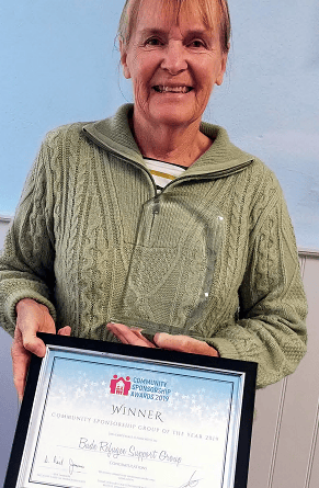 Mrs Mary Whibley, of the Bude Refugee Support Group, with a trophy and certificate marking its crowning as Community Sponsorship Group of the Year 2019
