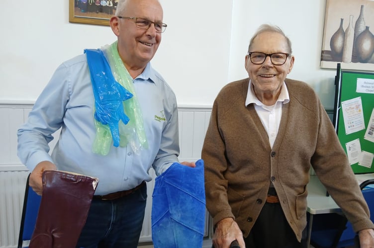 Whole lotta glove: retired vet Mr Mark Shepherd of Chilsworthy was the guest speaker at Holsworthy Methodist Church Thursday Friendship Group.  He is pictured with some of the vital props of his profession – protective gloves - and with audience member Mr Charlie Mann from Torrington