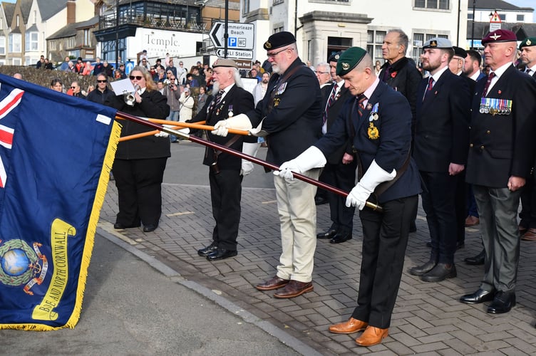 Standard Bearers Daz Logan (Bude Royal Marines Association), Phil Gavin (Royal Naval Association) and Binzy Reynolds (Royal British Legion Bude) lowers the standard as Emma Inch of Heartland Town Band sounds the Last Post and Reveille.